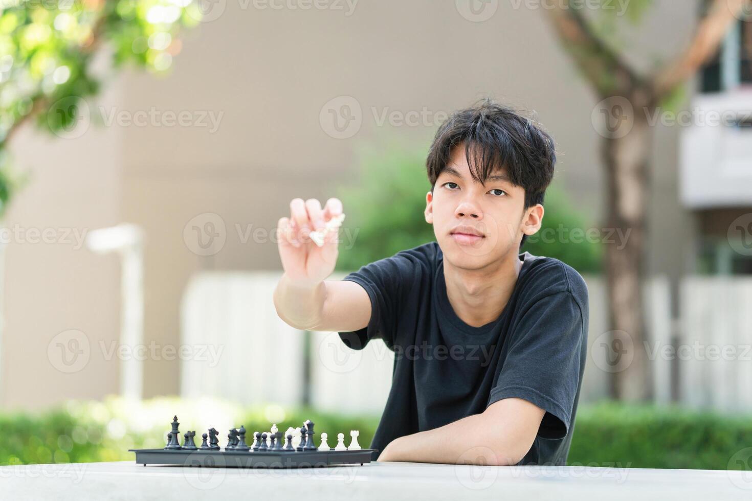 Asian teenage boy playing chess board, Asian boy relaxing hobbies playing a game of chess outdoor photo