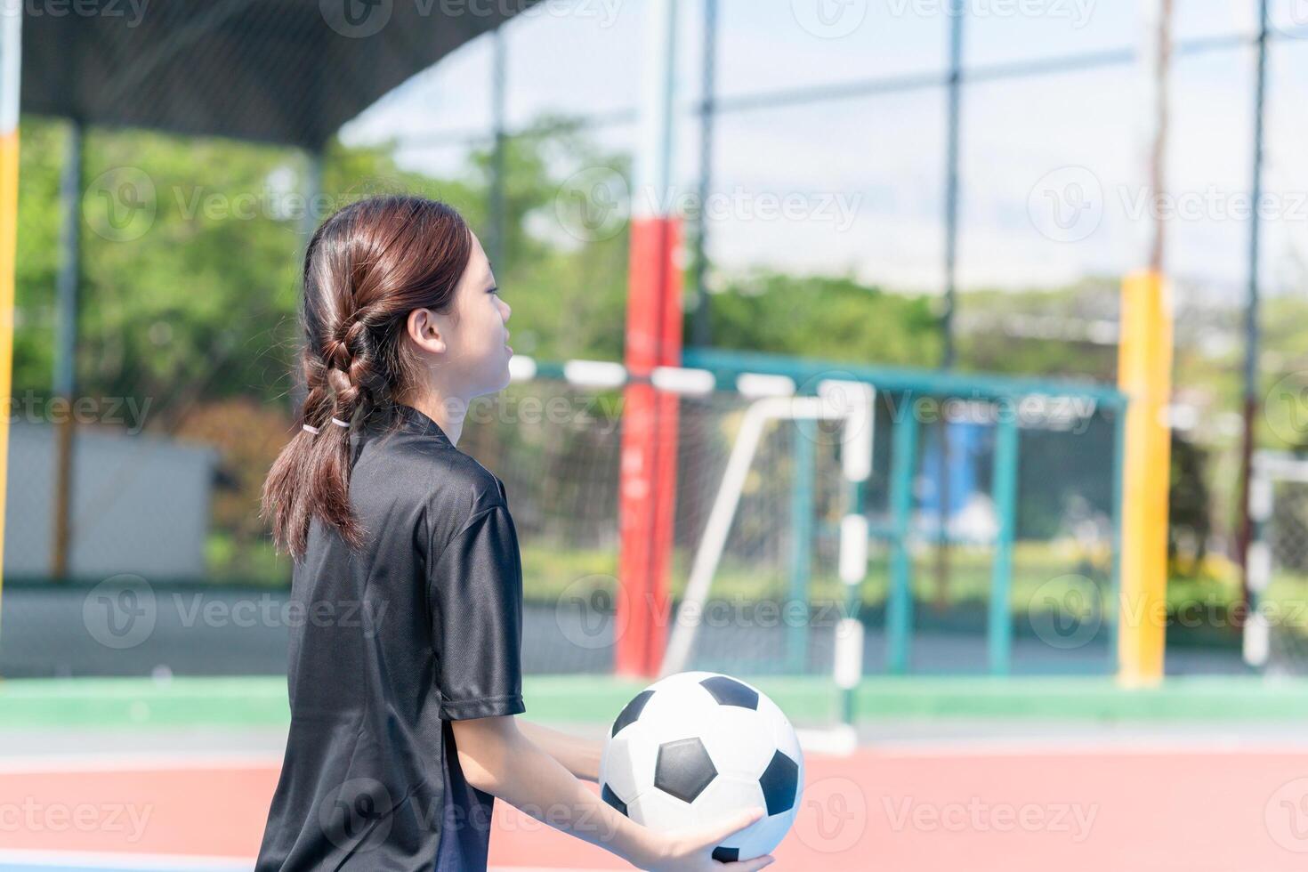 Asian child girl playing football in the urban outdoor futsal court photo
