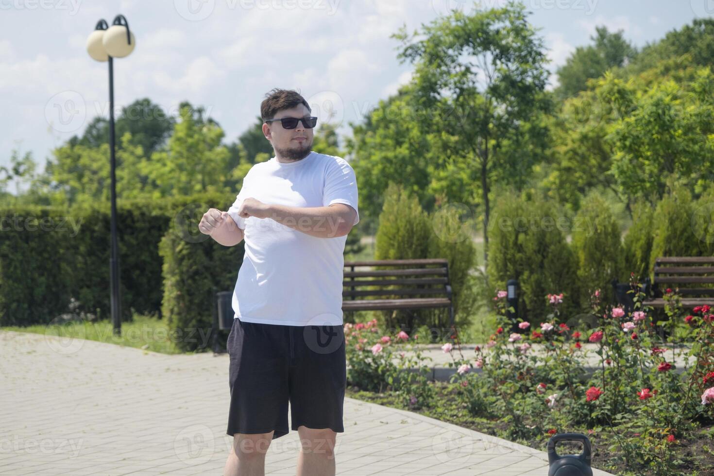 Sportive man workout with kettlebell outdoor in spring or summer photo