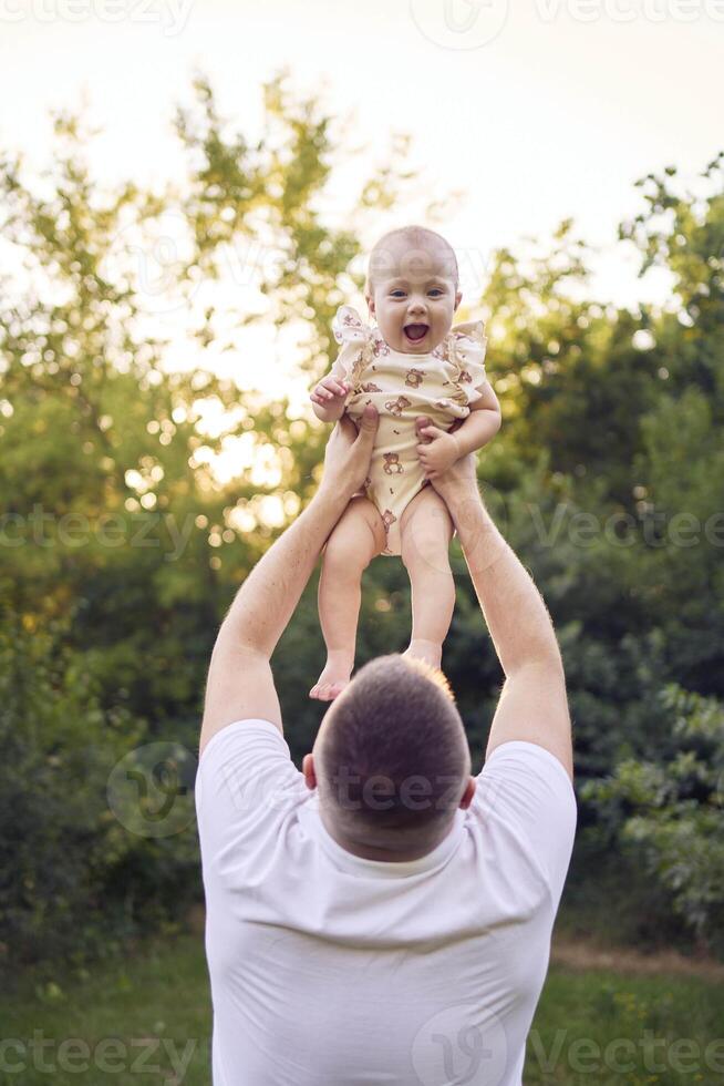 dad playing with his baby daughter in the garden photo