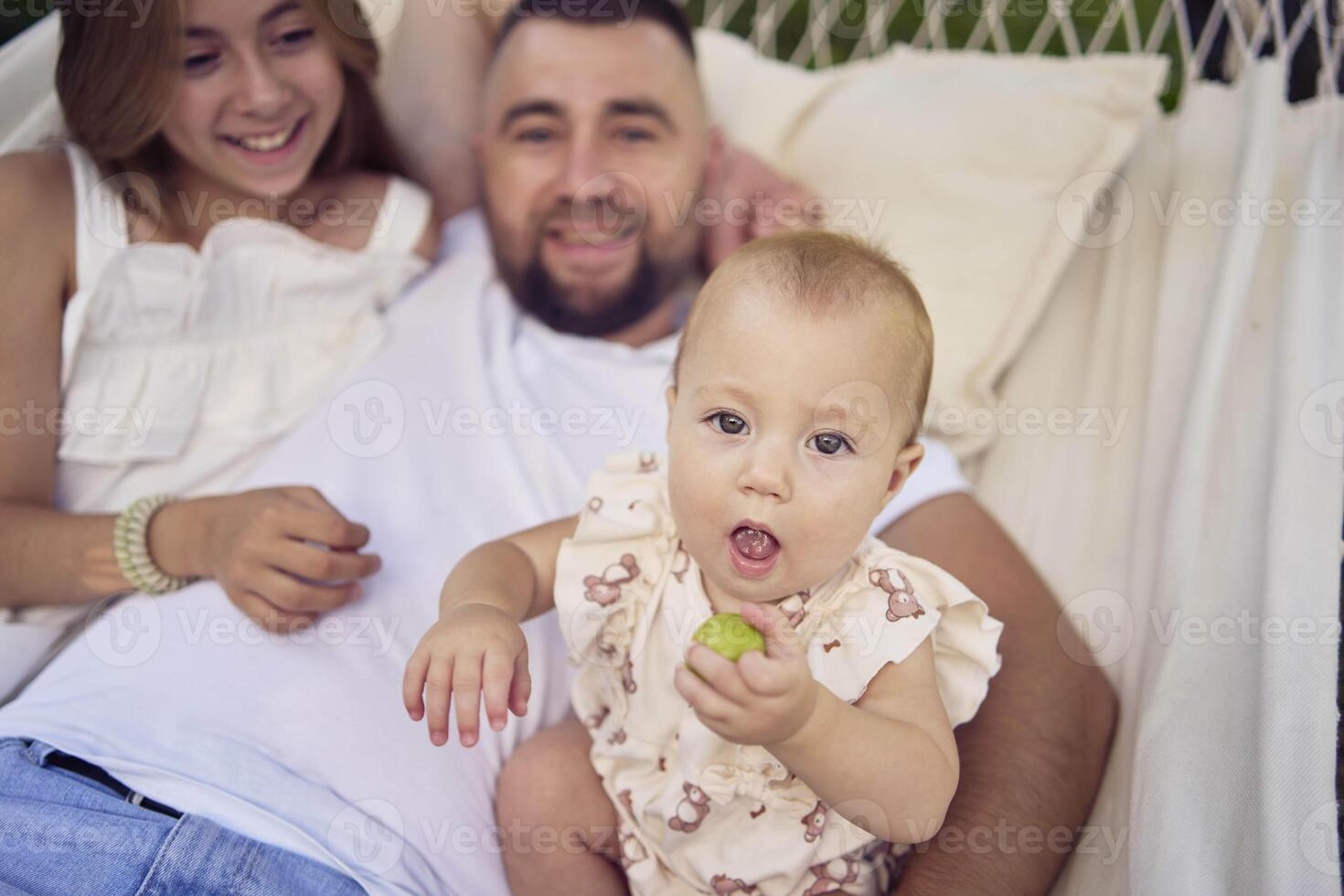 dad playing with his daughters, baby and teenager in a hammock photo