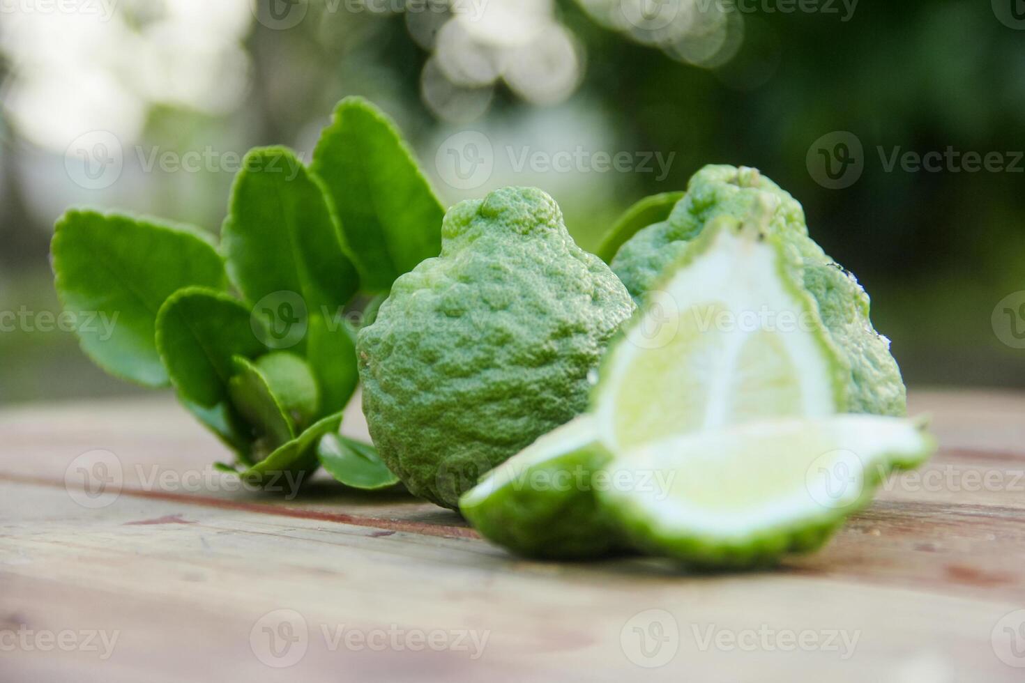 Bergamot fruits or sliced kaffir lime on wooden table and natural green background photo