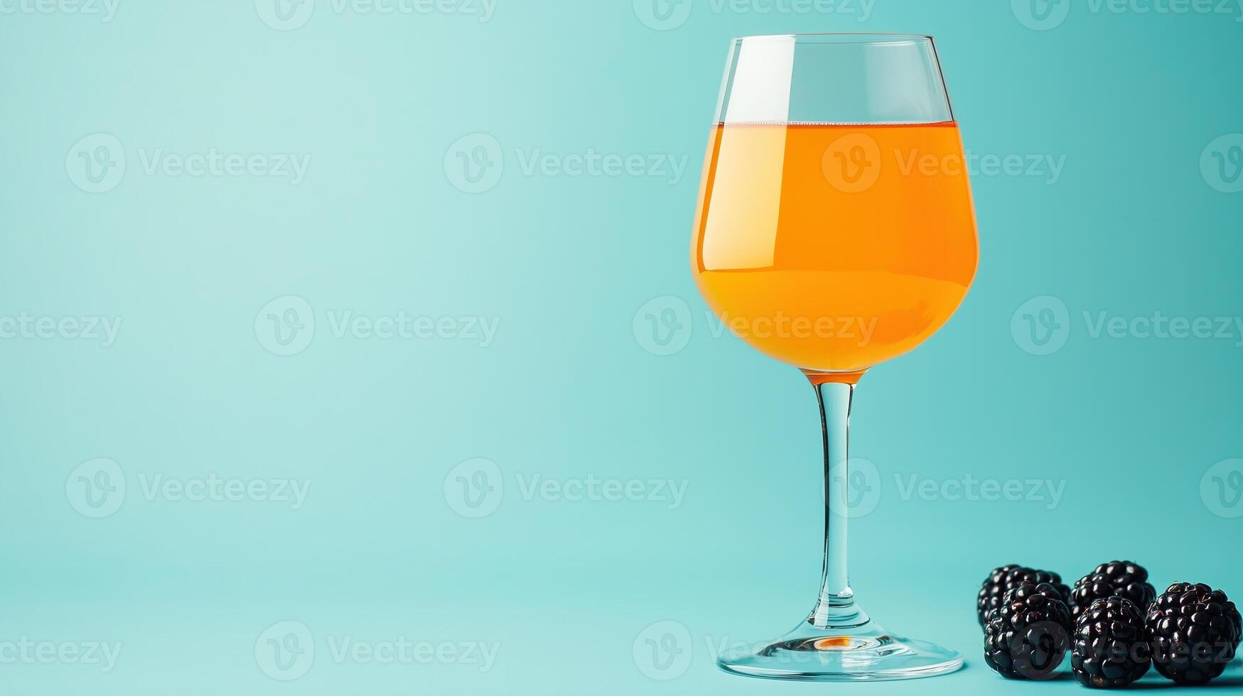 An orange wine glass with blackberries on a blue background photo