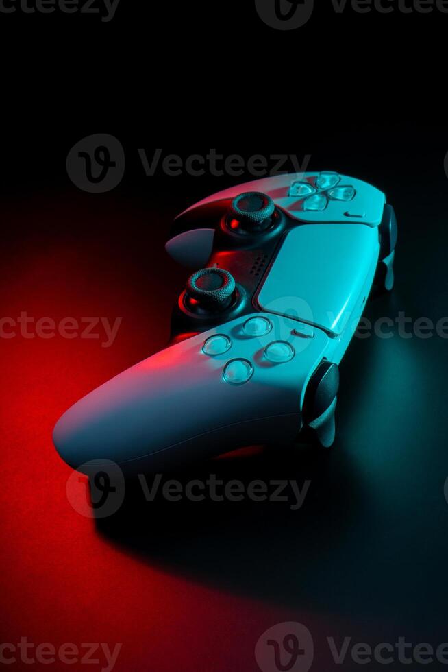 Modern white gamepad illuminated in red and blue. Game controller for games and e-sports on a dark back photo
