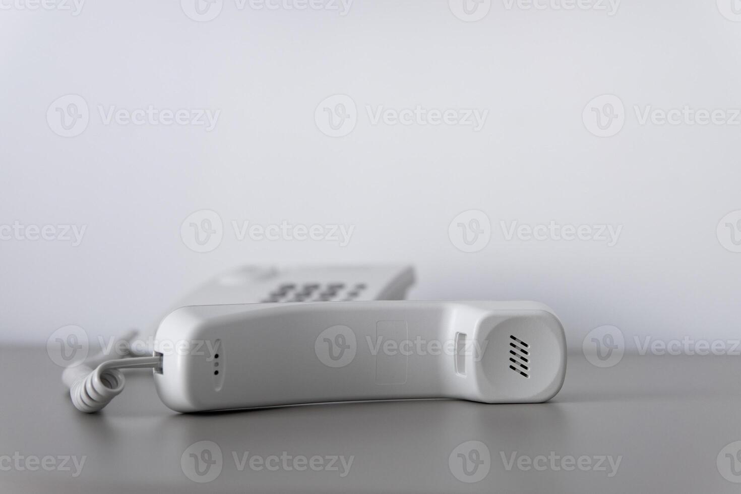 Modern white landline office phone with a hook. Technical support concept. No answer. Closeup white phone , office phone on the desk. Closeup white phone , office phone on the desk. photo