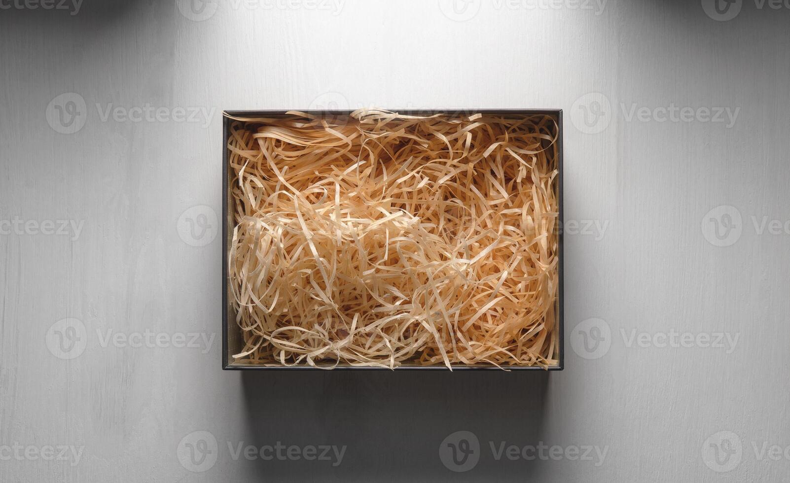 Top view of an open box with packing sawdust. Gift wrapping on the table. photo