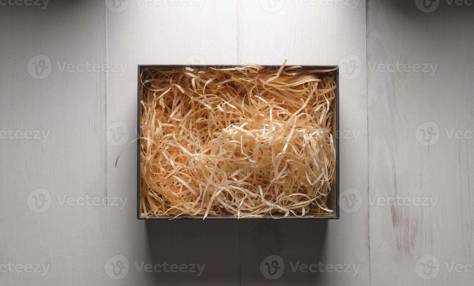 Top view of an open box with packing sawdust. Gift wrapping on the table. photo