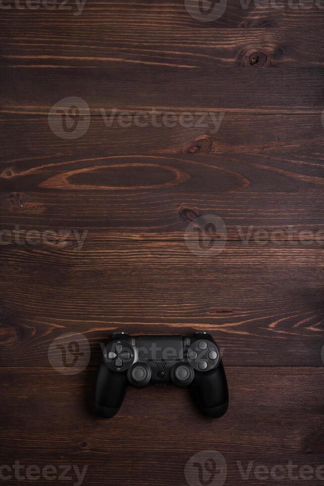 Modern black gamepad on a dark wooden background. Game concept with copy space for text. photo