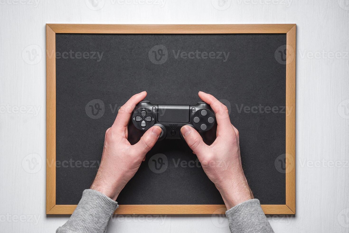 Hands hold new joystick on blackboard. Gamer play game with gamepad controller. photo