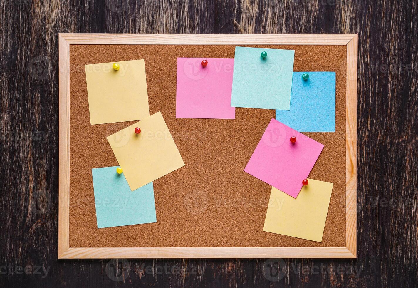 corkboard with pinned multicolored stickers on dark background photo