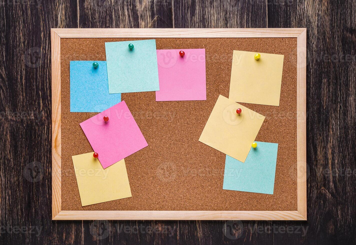 corkboard with pinned multicolored stickers on dark background photo