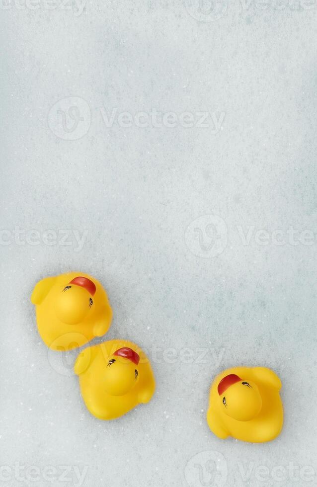 High Angle View of yellow rubber duck in bath swimming in foam water. Yellow rubber ducklings in soapy foam. photo