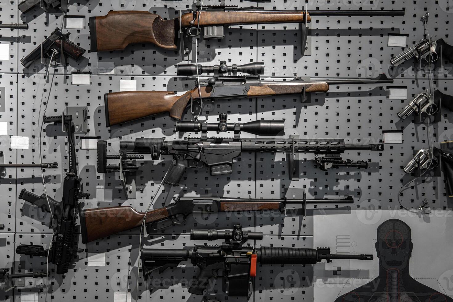 Collection of rifles and carbines. Various firearms hang on special mounts on the wall. Weapon back. photo