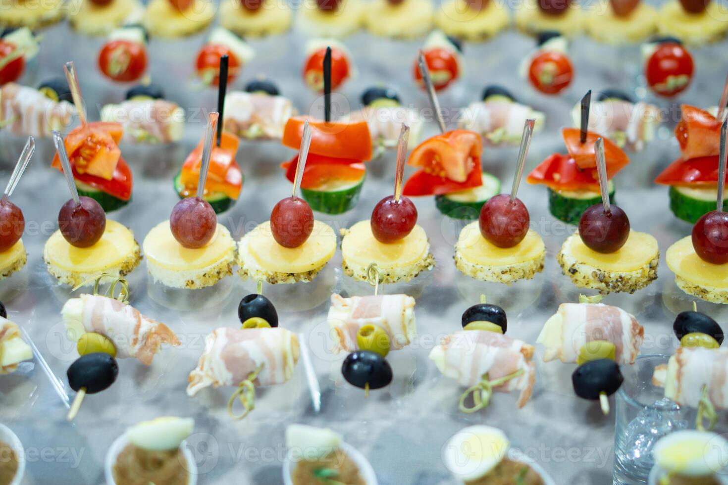 A variety of snacks and canapes are laid out on a glass table. Wickedly designed and laid out food. Holiday catering. Light back. photo