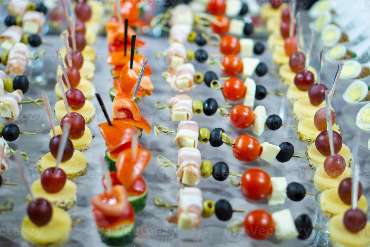 A variety of snacks and canapes are laid out on a glass table. Wickedly designed and laid out food. Holiday catering. Light back. photo