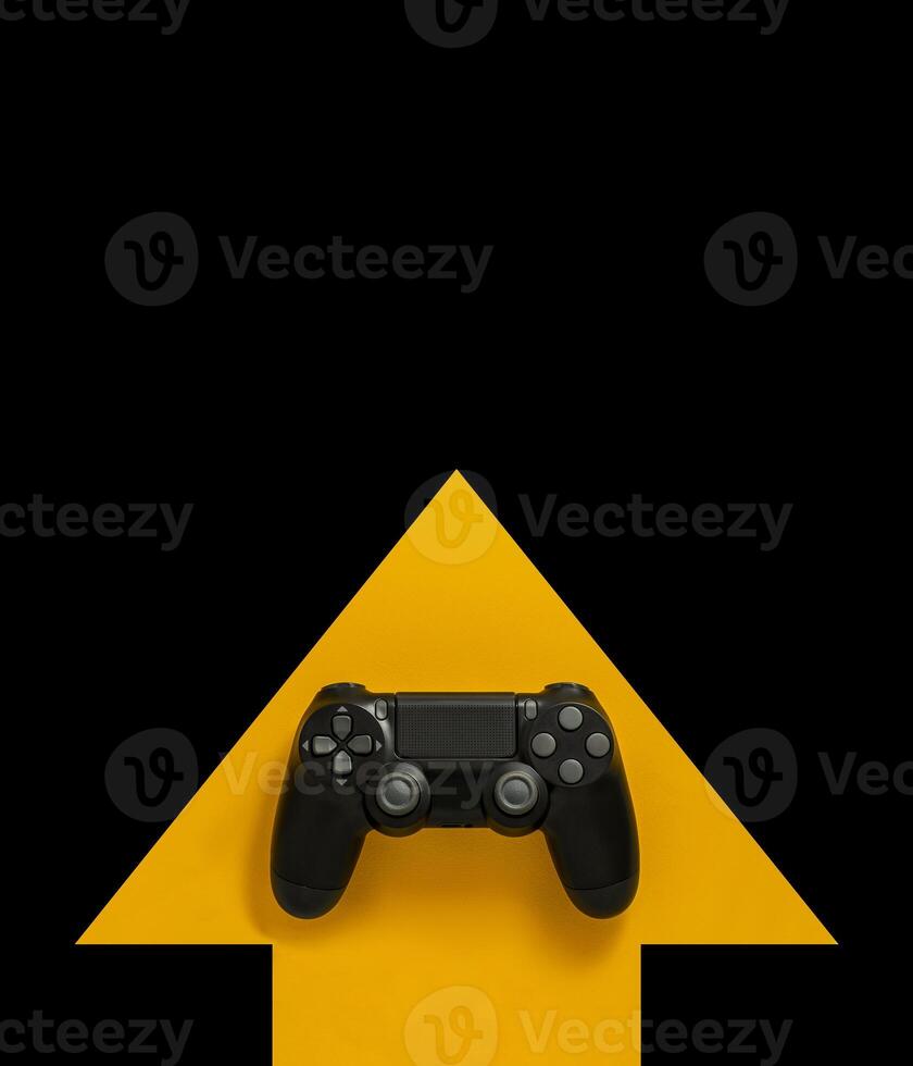 Modern black gamepad on a yellow arrow on a black background. Joystick on a yellow direction indicator on a dark background. Flat lay copyspace. photo