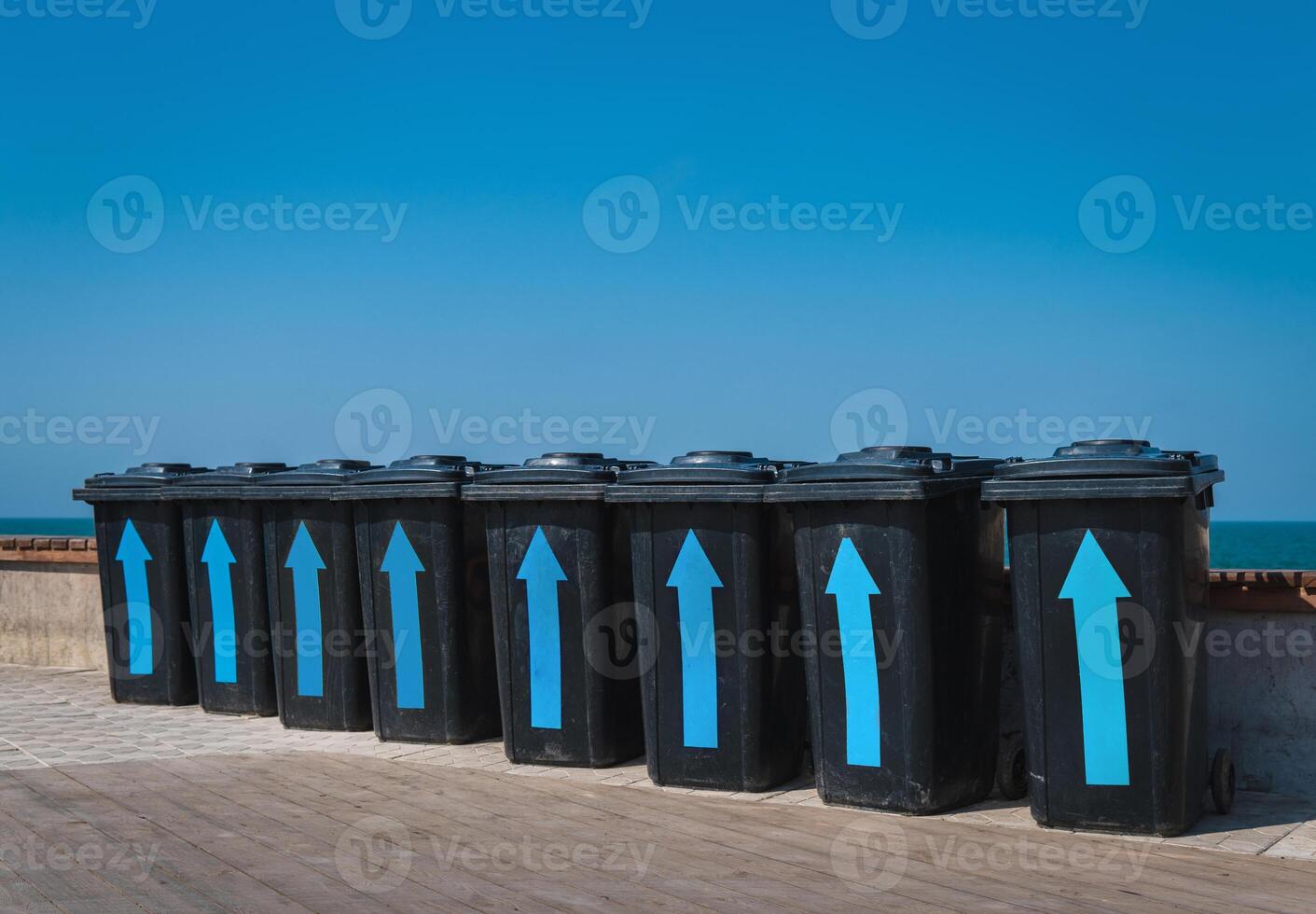 Black plastic garbage cans near the sea. Containers for different rubbish on a background of blue sky. Garbage sorting for further processing. photo
