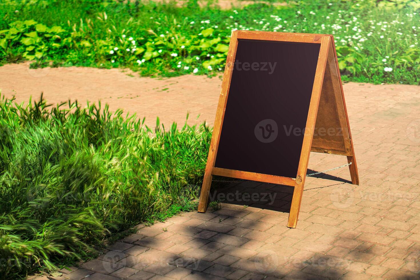 A black chalkboard stand on wood for a restaurant menu in the street. Empty menu board on street. Empty menu board on street on the pub or restaurant background. Beauty and minimalism style photo
