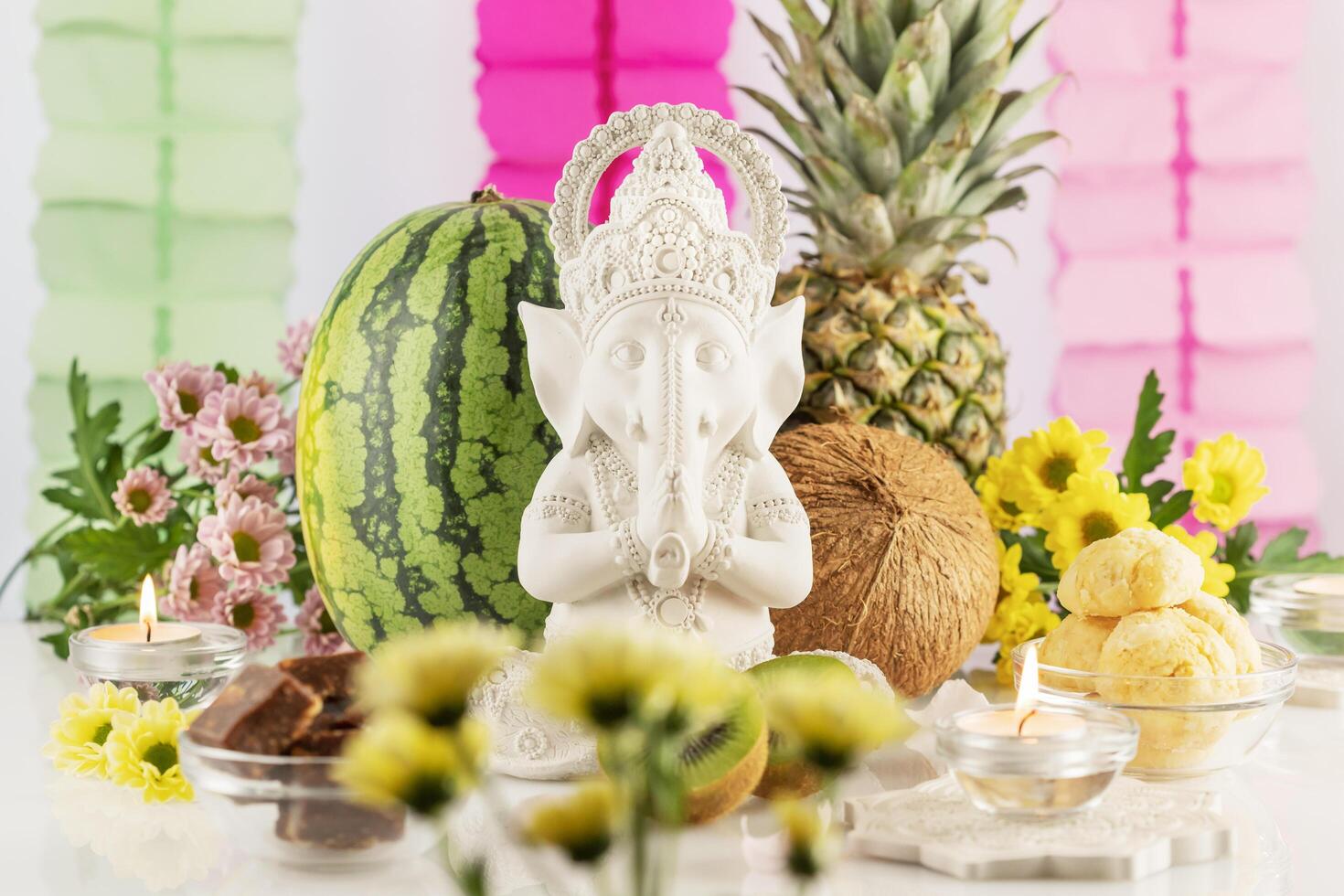 Sculpture of Lord Ganesha with fruits, candles and flowers photo