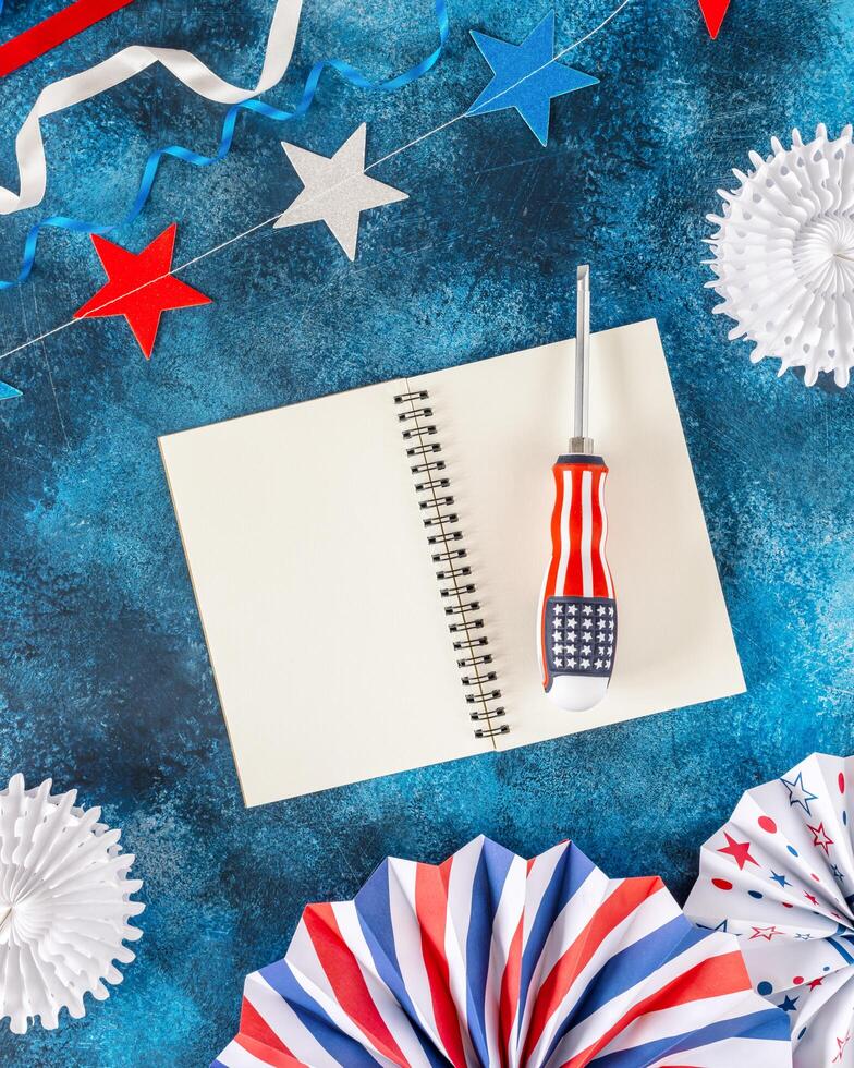 labor day flat lay with screwdriver, notepad with empty white sheets photo