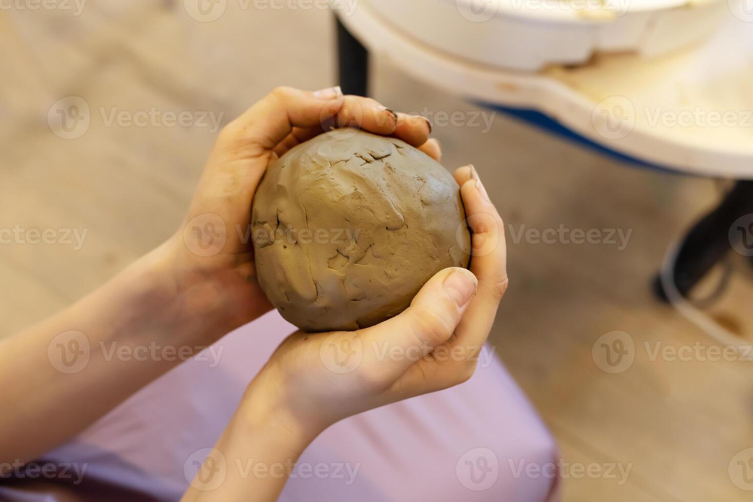 A child crushes a large piece of clay for modeling with his hands photo