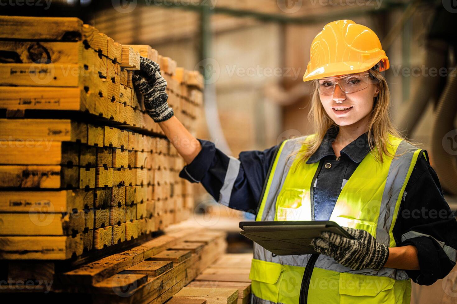 woman worker carpenter wearing safety uniform and hard hat working and checking the quality of wooden products at workshop manufacturing. man and woman workers wood in dark warehouse industry. photo