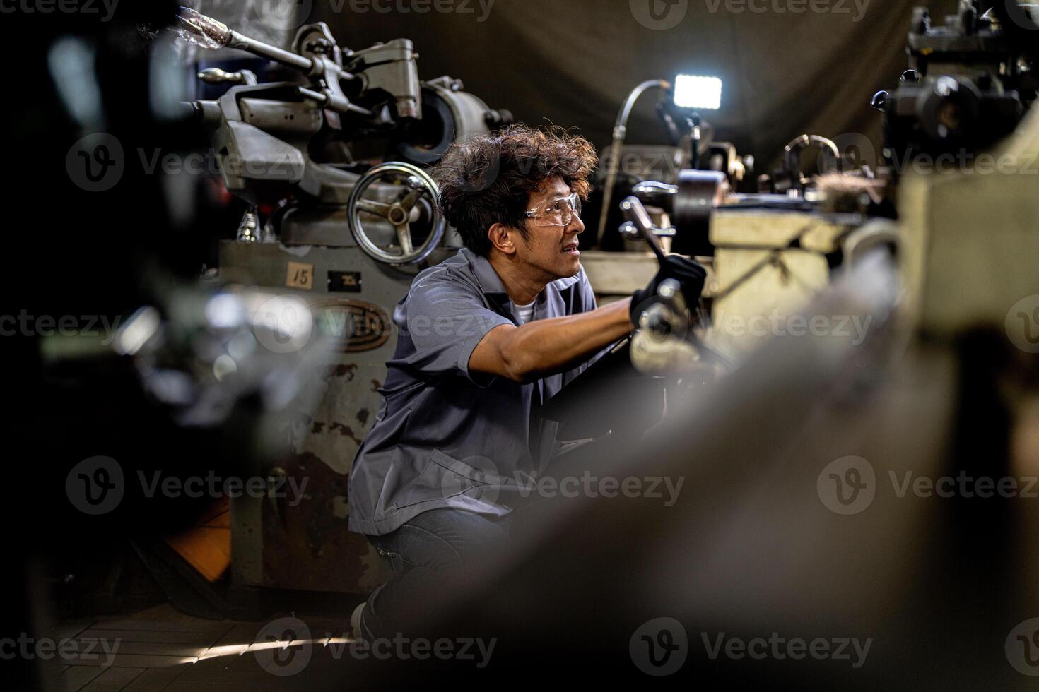 Asian worker in production plant drilling at machine. Professional worker near drilling machine on factory. finishing metal working internal steel surface on lathe grinder machine with flying sparks. photo