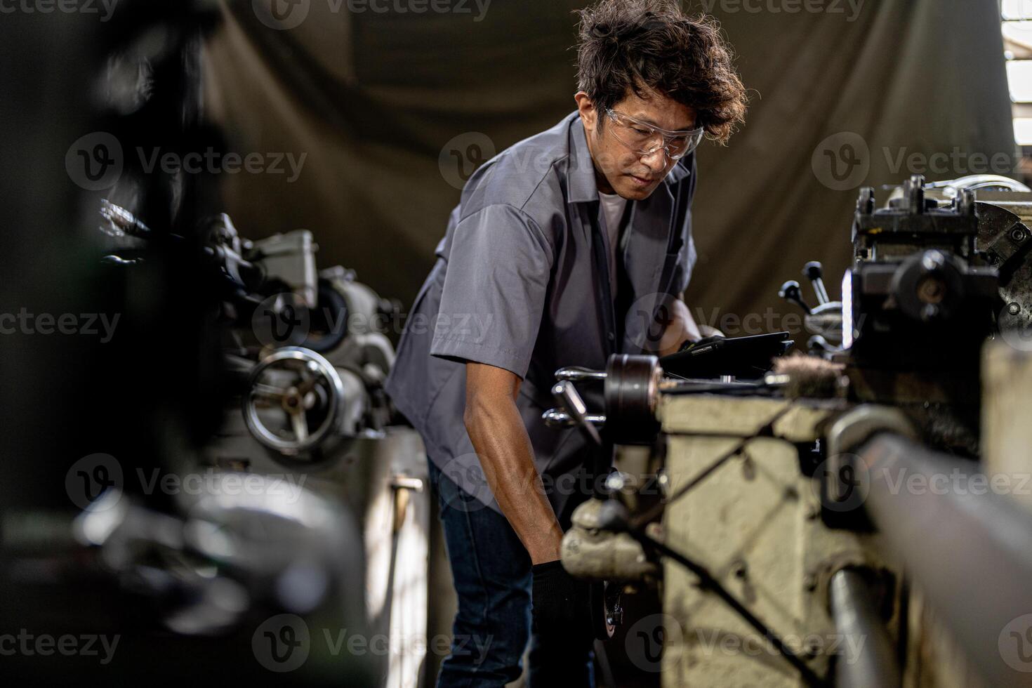 Asian worker in production plant drilling at machine. Professional worker near drilling machine on factory. finishing metal working internal steel surface on lathe grinder machine with flying sparks. photo