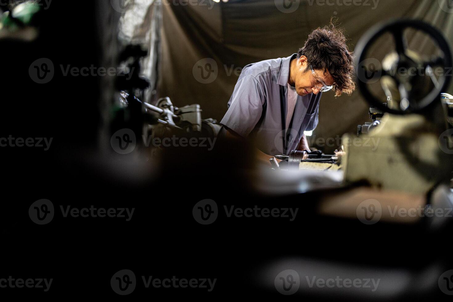 Asian worker in production plant drilling at machine. Professional worker near drilling machine on factory. finishing metal working internal steel surface on lathe grinder machine with flying sparks. photo