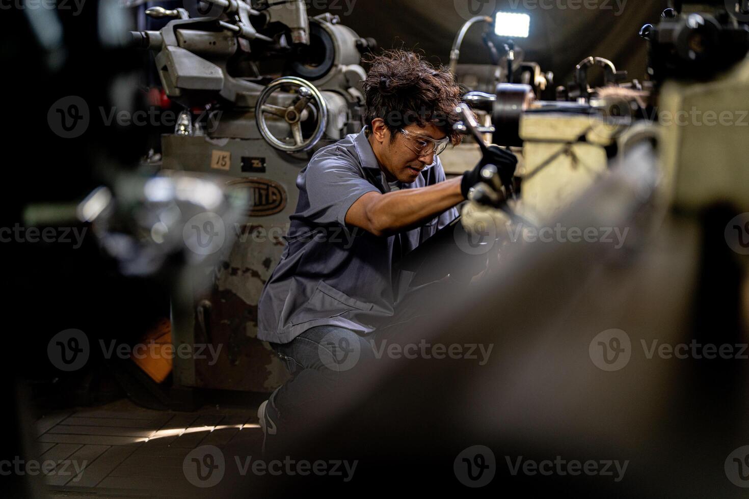 Asian worker in production plant drilling at machine. Professional worker near drilling machine on factory. finishing metal working internal steel surface on lathe grinder machine with flying sparks. photo