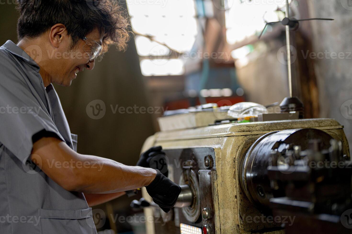 Asian worker in production plant drilling at machine. Professional worker near drilling machine on factory. finishing metal working internal steel surface on lathe grinder machine with flying sparks. photo