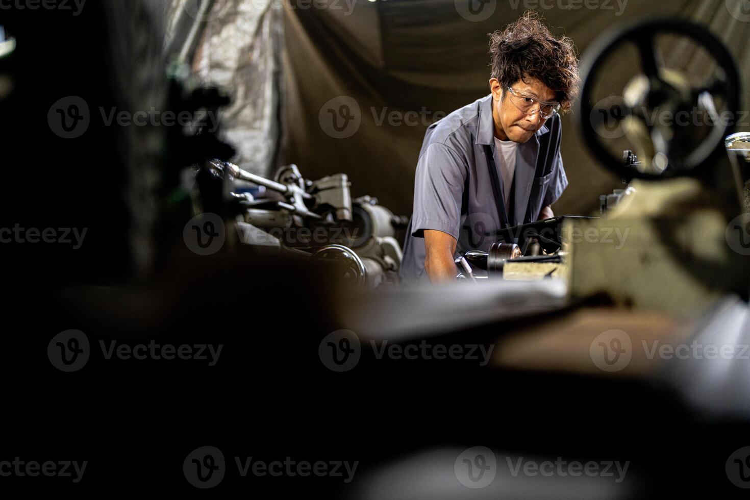 Asian worker in production plant drilling at machine. Professional worker near drilling machine on factory. finishing metal working internal steel surface on lathe grinder machine with flying sparks. photo