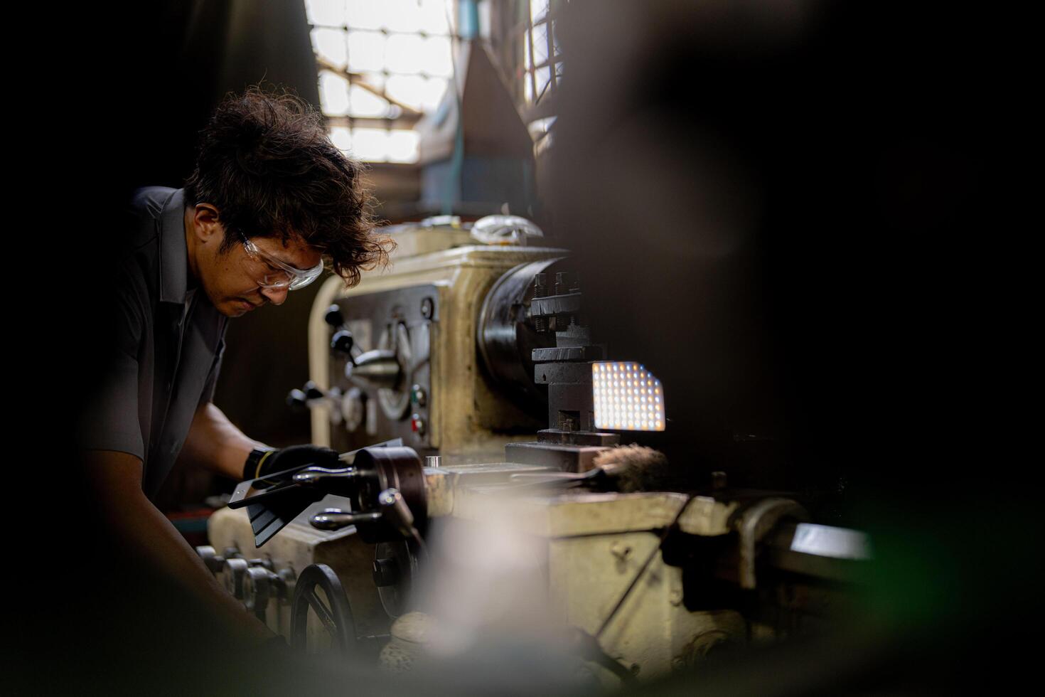 Asian worker in production plant drilling at machine. Professional worker near drilling machine on factory. finishing metal working internal steel surface on lathe grinder machine with flying sparks. photo