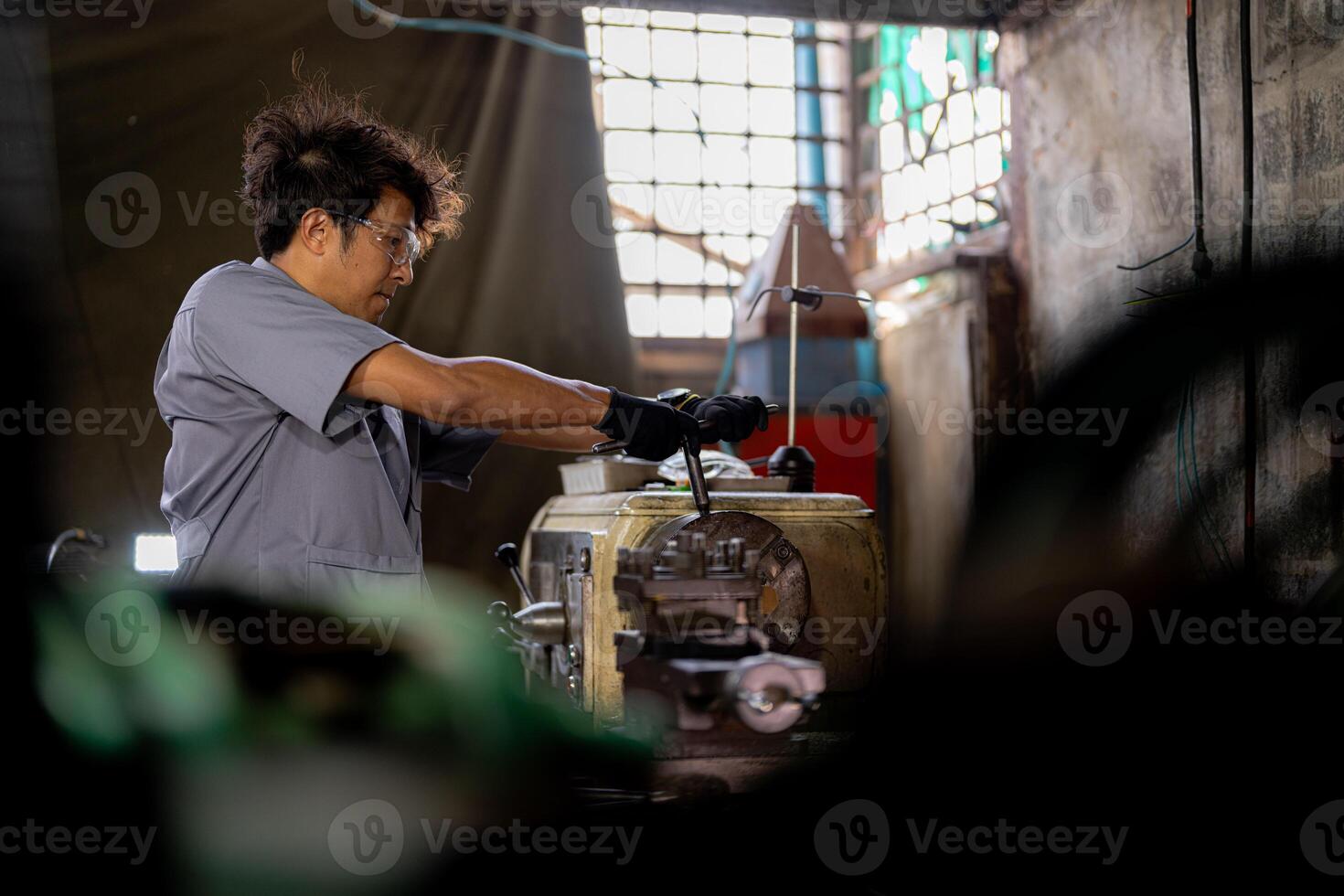 Asian worker in production plant drilling at machine. Professional worker near drilling machine on factory. finishing metal working internal steel surface on lathe grinder machine with flying sparks. photo