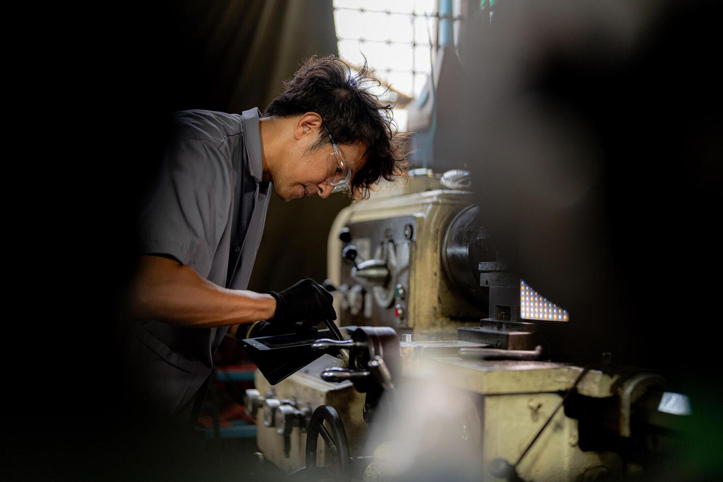 Asian worker in production plant drilling at machine. Professional worker near drilling machine on factory. finishing metal working internal steel surface on lathe grinder machine with flying sparks. photo