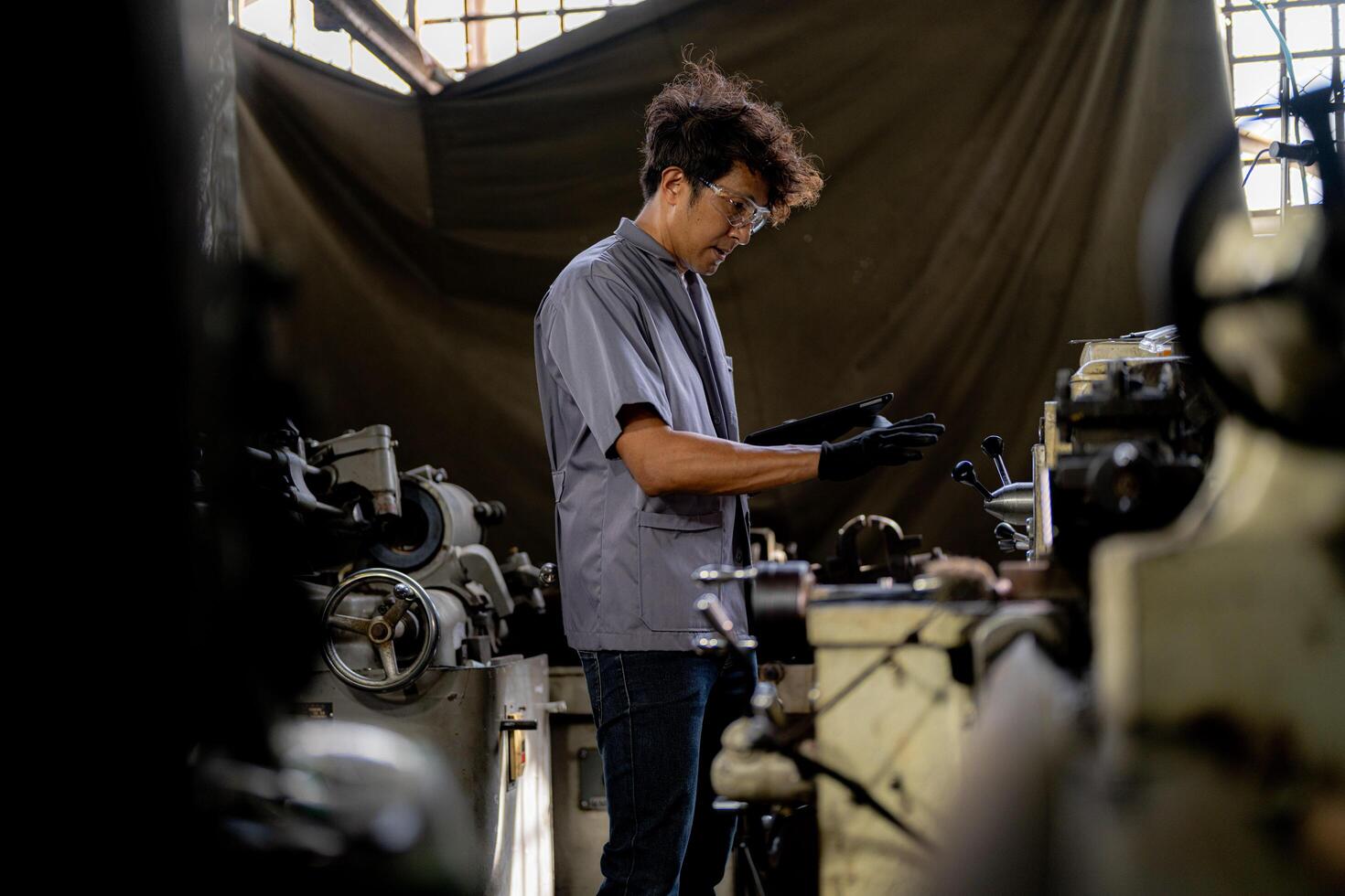 Asian worker in production plant drilling at machine. Professional worker near drilling machine on factory. finishing metal working internal steel surface on lathe grinder machine with flying sparks. photo