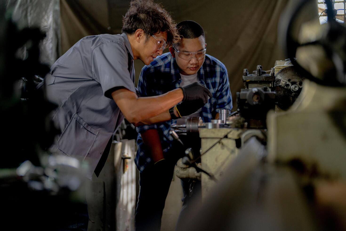 Men are inspecting steel parts for machine installation. team of teacher and student are learning to use heavy machines in steel factory. workers cooperate while doing quality control of manufactured. photo