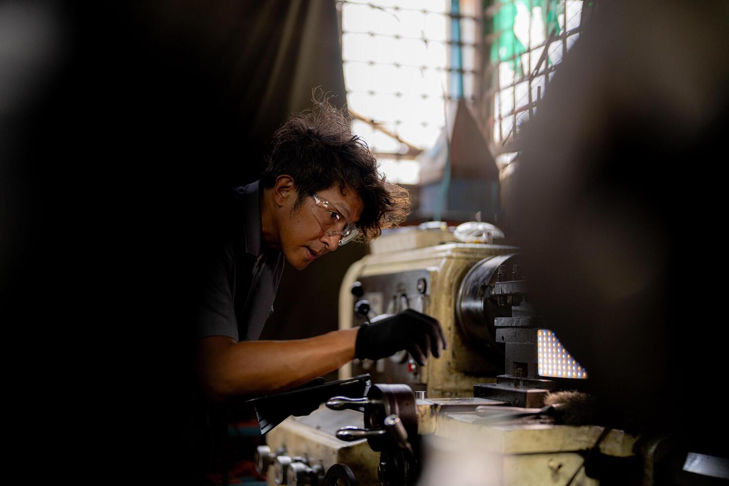 Asian worker in production plant drilling at machine. Professional worker near drilling machine on factory. finishing metal working internal steel surface on lathe grinder machine with flying sparks. photo