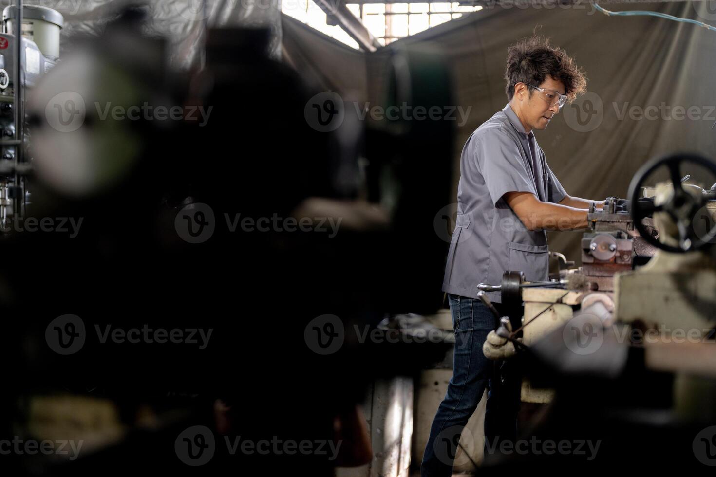 Asian worker in production plant drilling at machine. Professional worker near drilling machine on factory. finishing metal working internal steel surface on lathe grinder machine with flying sparks. photo