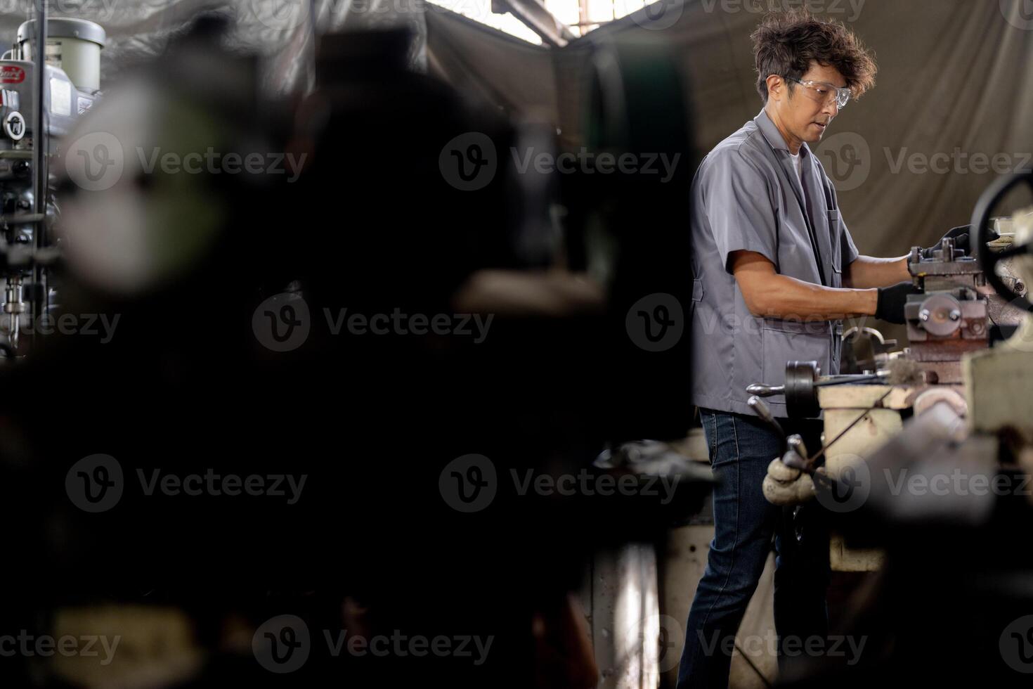 Asian worker in production plant drilling at machine. Professional worker near drilling machine on factory. finishing metal working internal steel surface on lathe grinder machine with flying sparks. photo