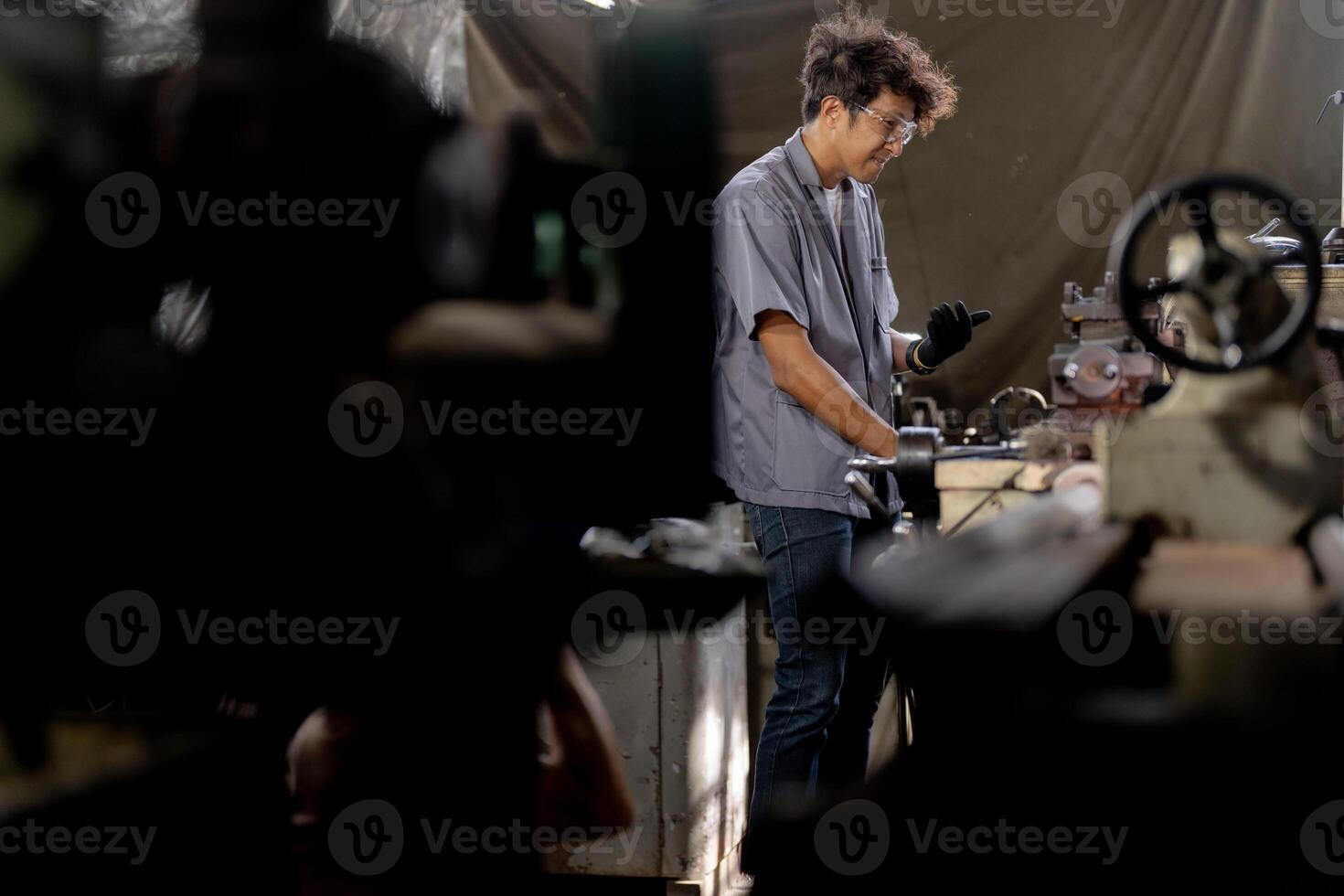 Asian worker in production plant drilling at machine. Professional worker near drilling machine on factory. finishing metal working internal steel surface on lathe grinder machine with flying sparks. photo