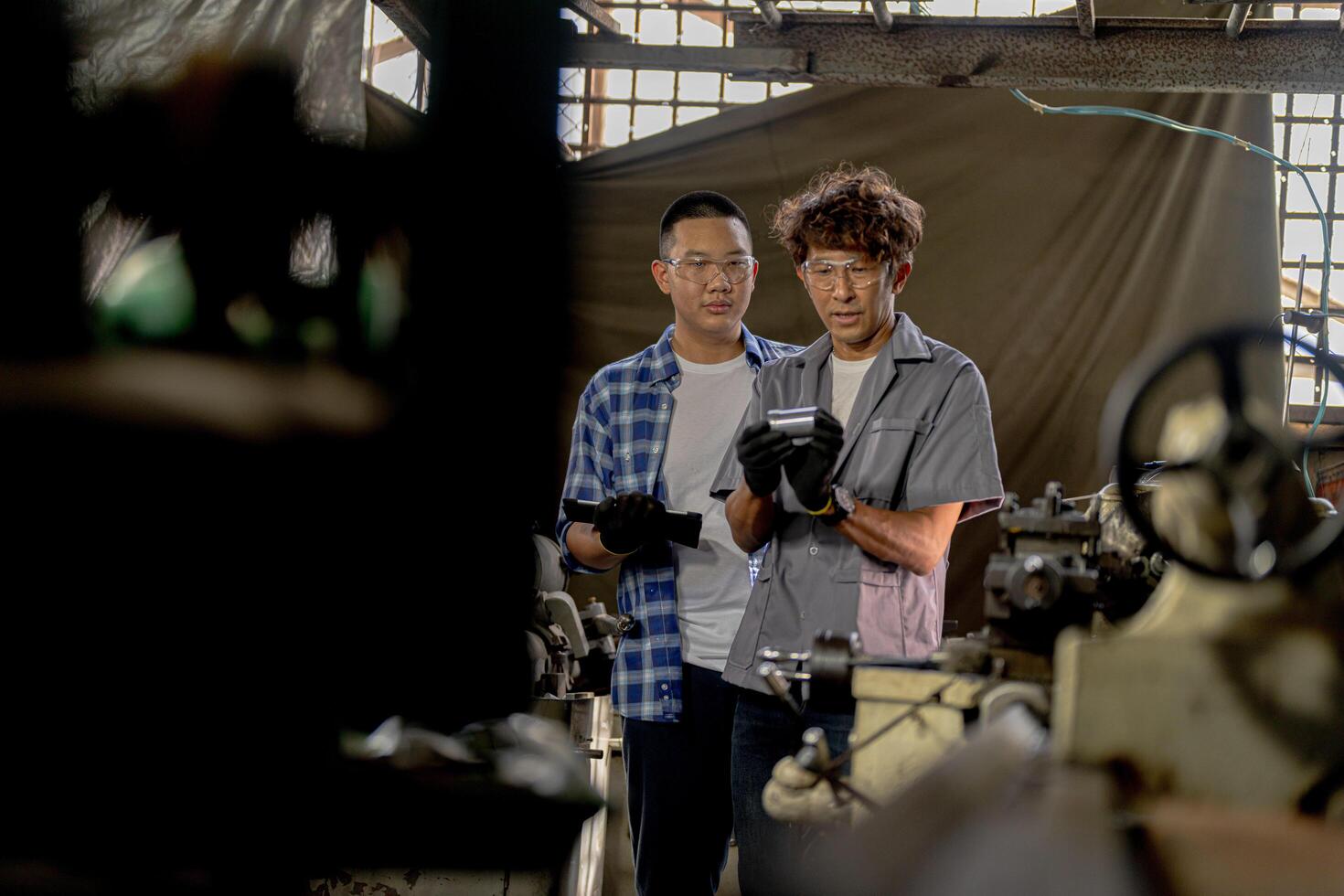 Men are inspecting steel parts for machine installation. team of teacher and student are learning to use heavy machines in steel factory. workers cooperate while doing quality control of manufactured. photo