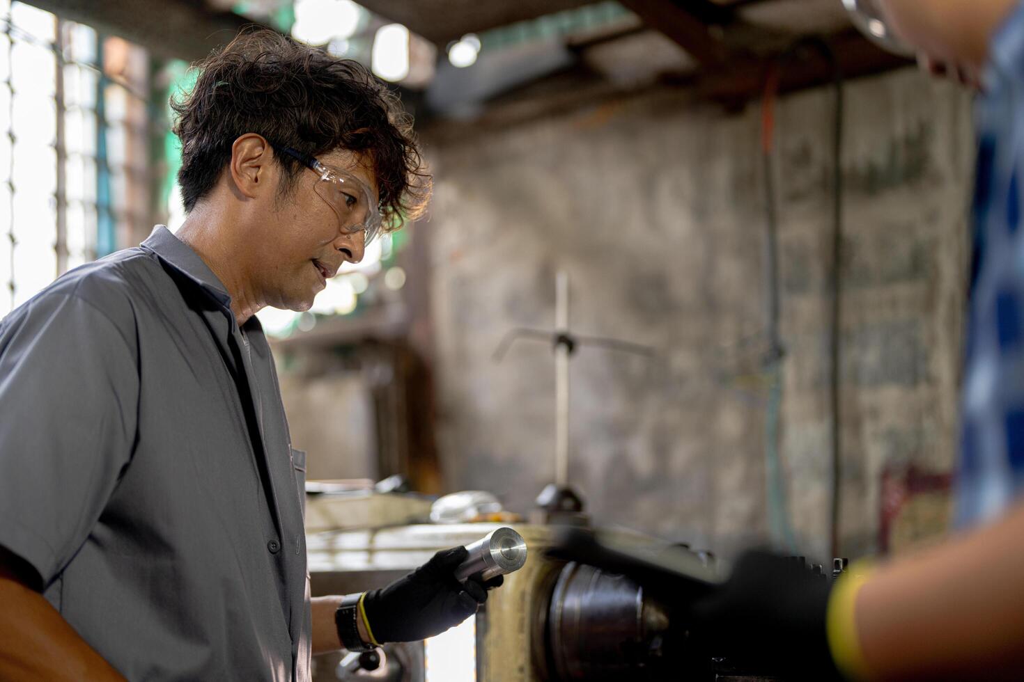 Men are inspecting steel parts for machine installation. team of teacher and student are learning to use heavy machines in steel factory. workers cooperate while doing quality control of manufactured. photo