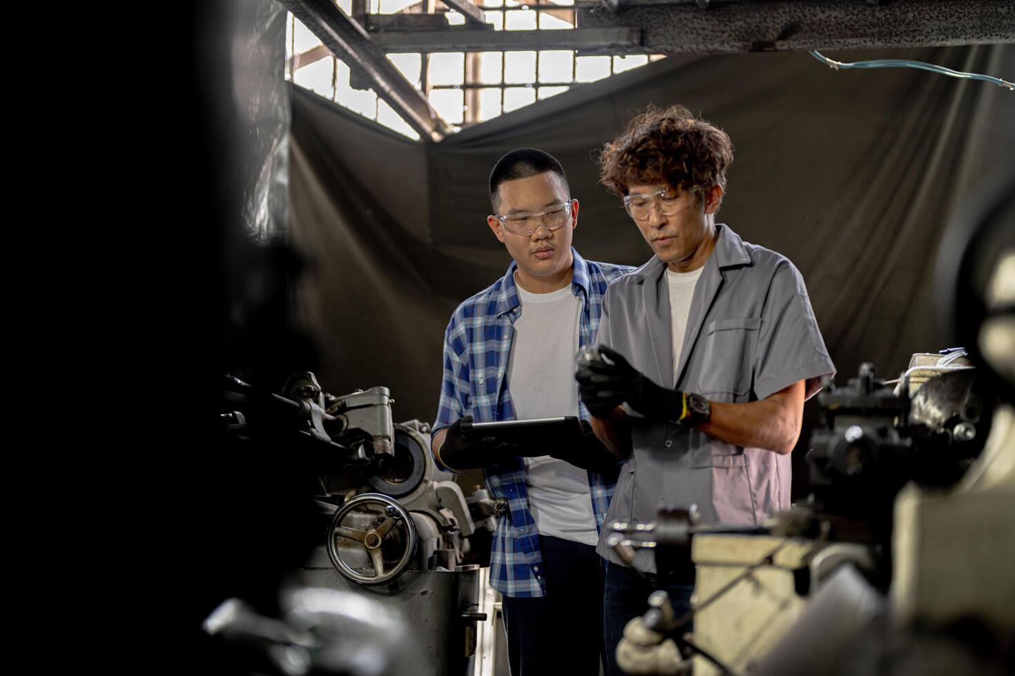 Men are inspecting steel parts for machine installation. team of teacher and student are learning to use heavy machines in steel factory. workers cooperate while doing quality control of manufactured. photo