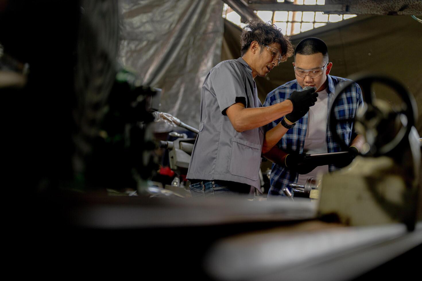 Men are inspecting steel parts for machine installation. team of teacher and student are learning to use heavy machines in steel factory. workers cooperate while doing quality control of manufactured. photo