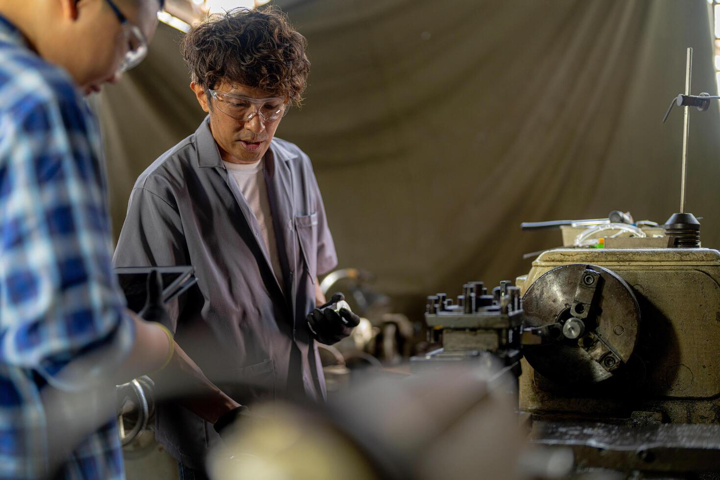 Men are inspecting steel parts for machine installation. team of teacher and student are learning to use heavy machines in steel factory. workers cooperate while doing quality control of manufactured. photo