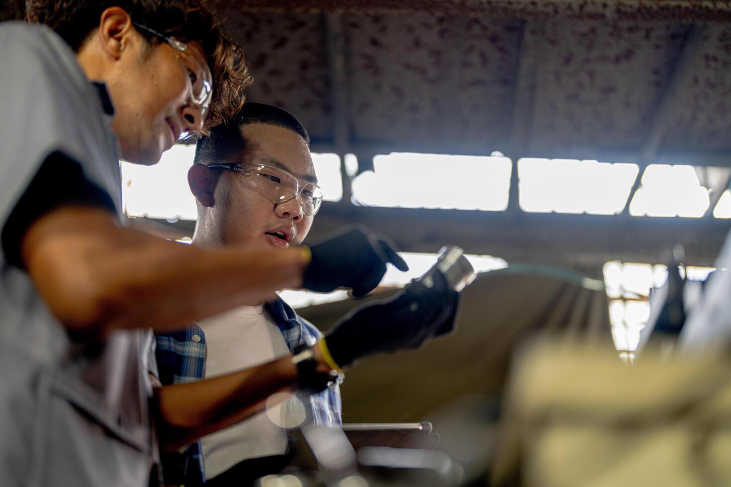 Men are inspecting steel parts for machine installation. team of teacher and student are learning to use heavy machines in steel factory. workers cooperate while doing quality control of manufactured. photo