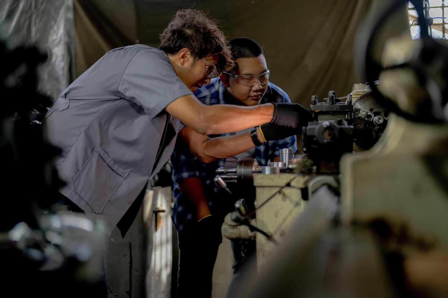 Men are inspecting steel parts for machine installation. team of teacher and student are learning to use heavy machines in steel factory. workers cooperate while doing quality control of manufactured. photo