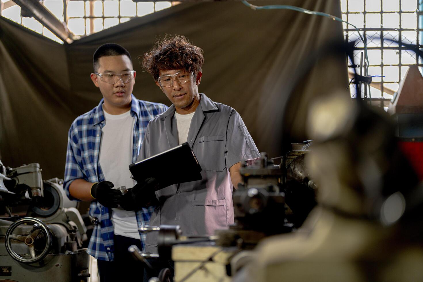 Men are inspecting steel parts for machine installation. team of teacher and student are learning to use heavy machines in steel factory. workers cooperate while doing quality control of manufactured. photo
