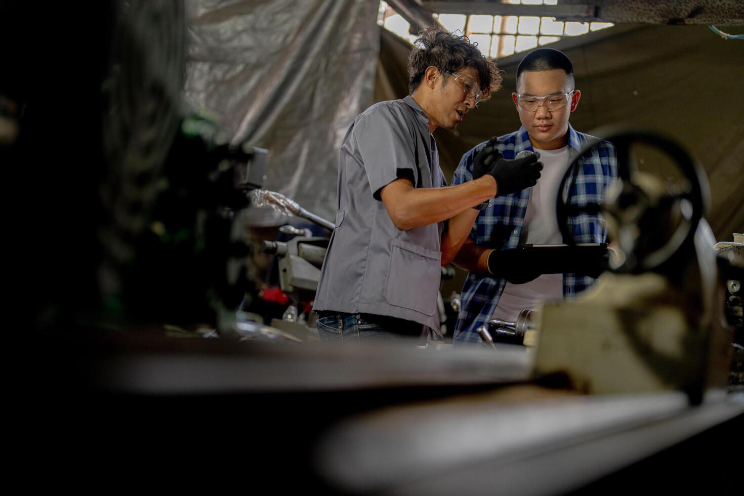 Men are inspecting steel parts for machine installation. team of teacher and student are learning to use heavy machines in steel factory. workers cooperate while doing quality control of manufactured. photo